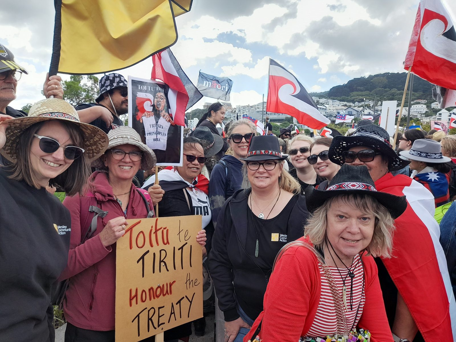 Wesley kaimahi at the hīkoi against the Treaty Principles Bill, holding a sign reading Toitū te Tiriti, Honour the Treaty.